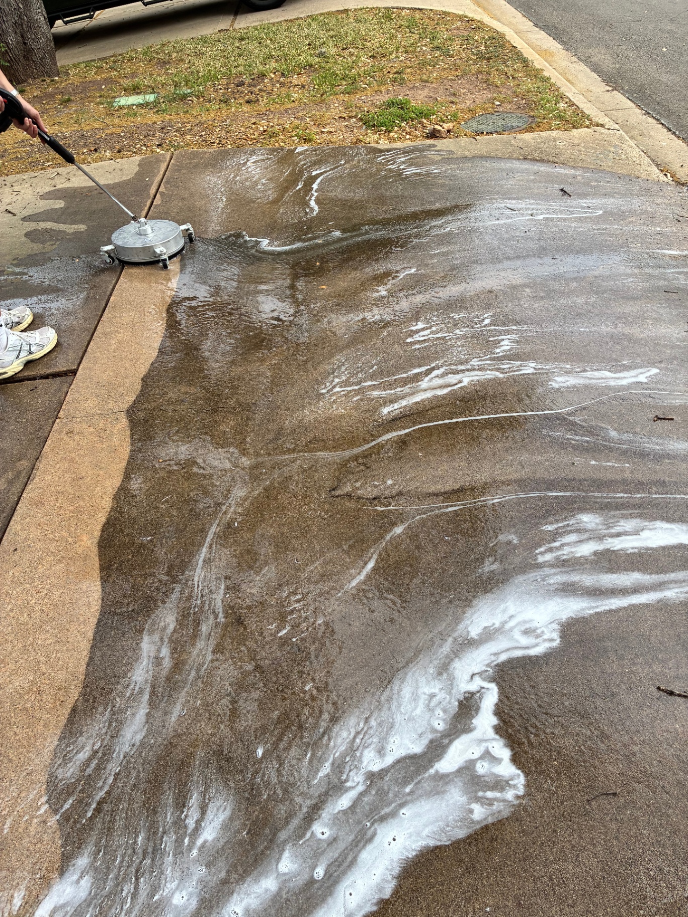 Surface cleaner mid-job on a concrete driveway