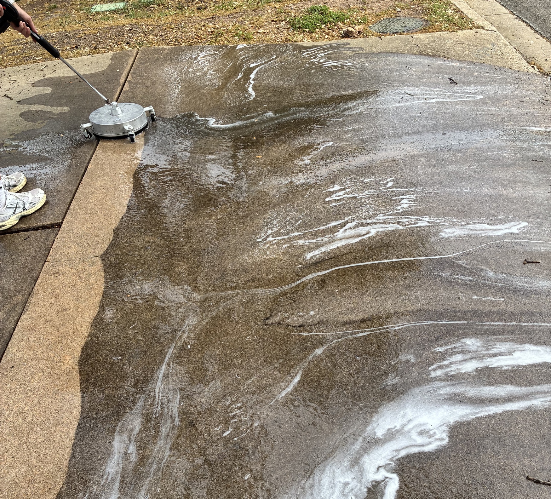 Surface cleaner mid-job on a concrete driveway